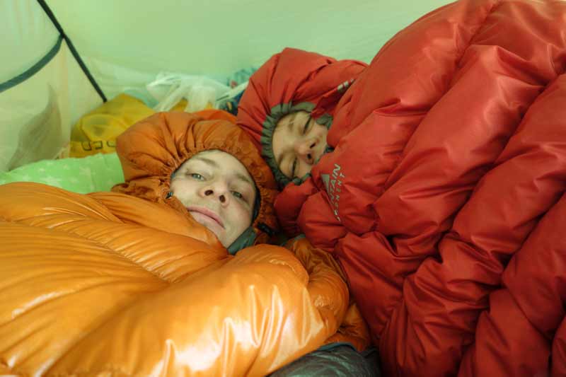 Zwei Personen mit Schlafsäcken im Zelt
