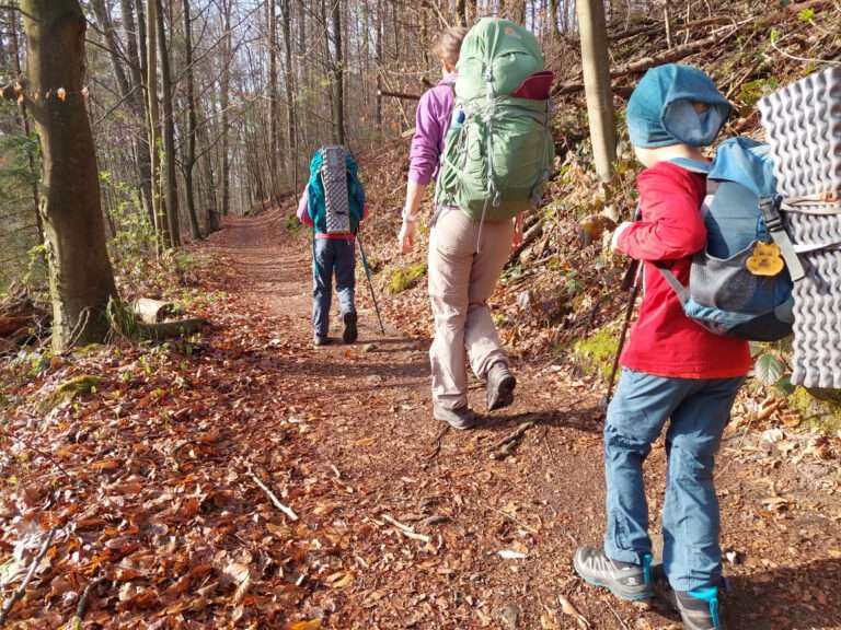 Kinder laufen mit Rucksäcken auf einem Wanderweg